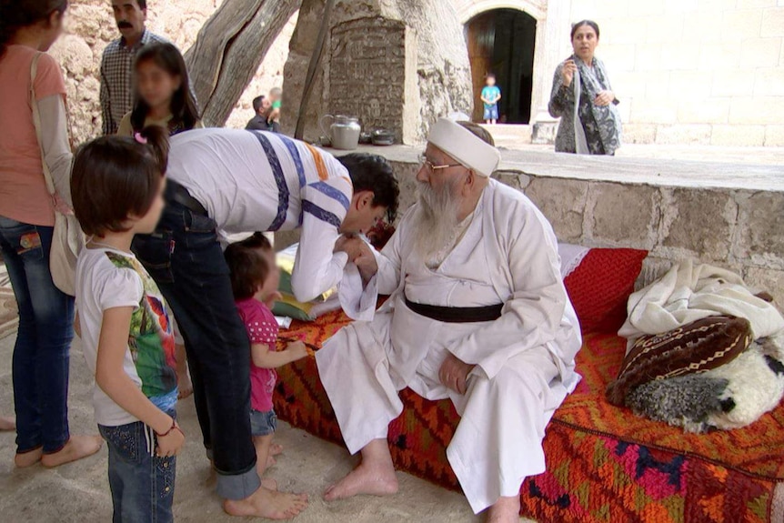 Yazidi spiritual leader Baba Sheikh surrounded by adults and children