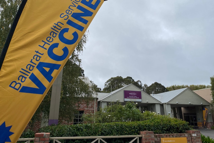 A hotel with a flag out front reading "vaccine"