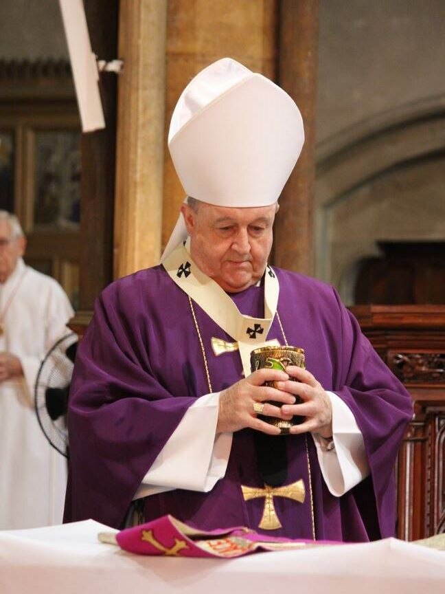 Archbishop Philip Wilson holds communion wine.