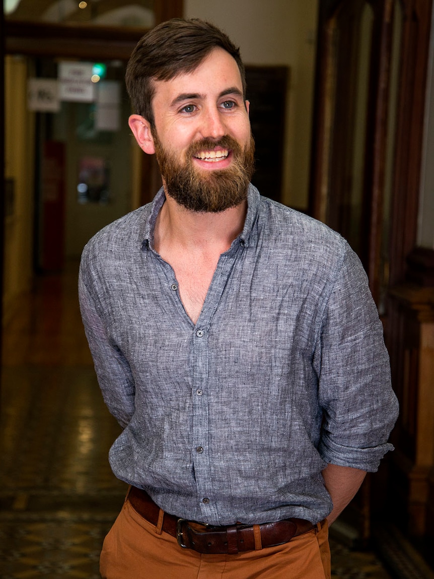 A man with a beard smiles at someone to the right of the camera