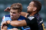 A NSW Waratahs player holds the ball as he is tackled around his upper body by a Chiefs opponent in Super Rugby.