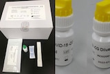 An unwrapped COVID-19 at-home test kit next to two bottles of diluting agent.