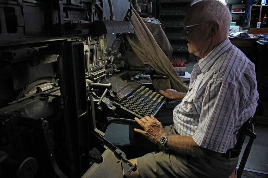 Mature-aged man sitting behind a linotype machine.