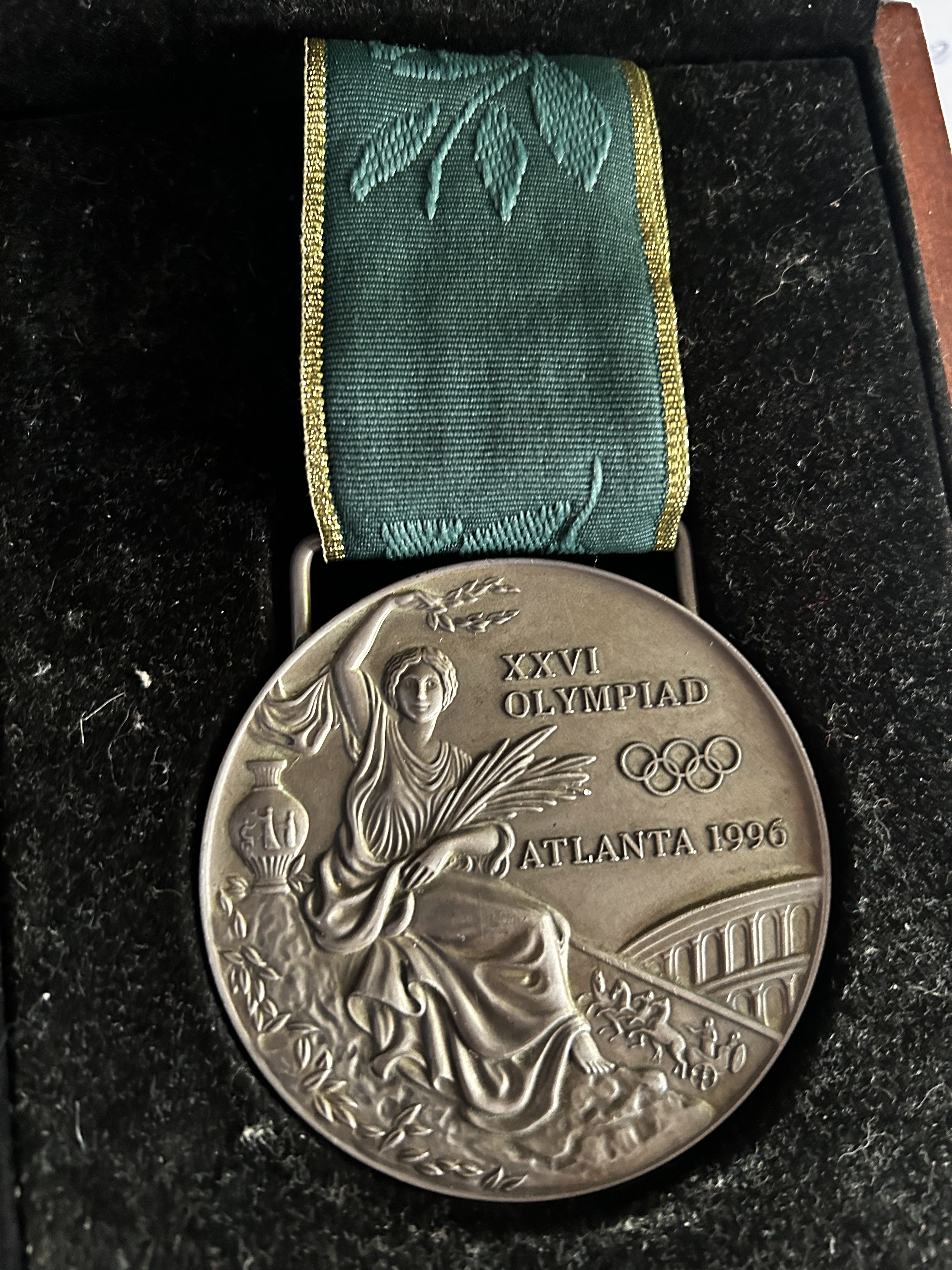 A silver Olympic medal for the 1996 Olympics held in Atlanta inside a black velvet case.