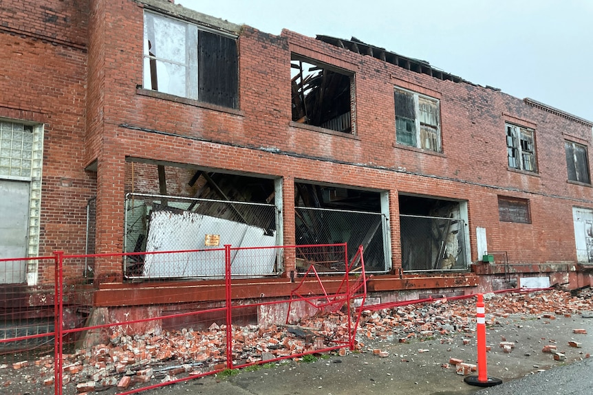 A building with shattered windows and debris below