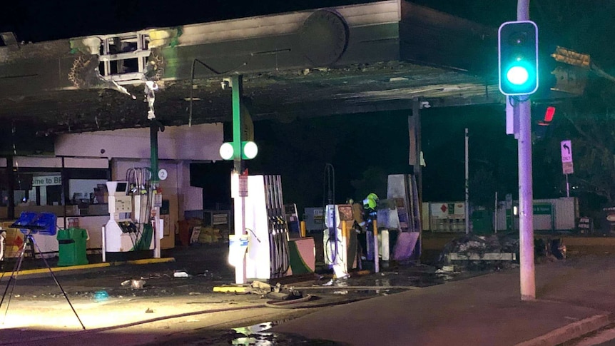 The petrol station awning is charred black from the fire.