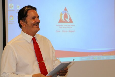 Dark haired man with moustache in white shirt and red tie