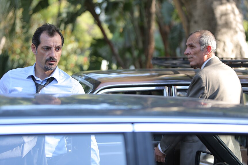 Still image of Adel Karam and Kamel El Basha standing by their parked cars in 2018 film The Insult.