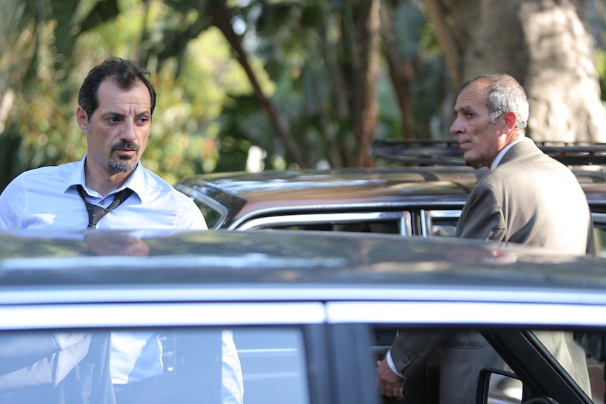 Still image of Adel Karam and Kamel El Basha standing by their parked cars in 2018 film The Insult.