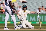 An Australian batsman kneels looking up after diving and failing to make his ground in a Test match.