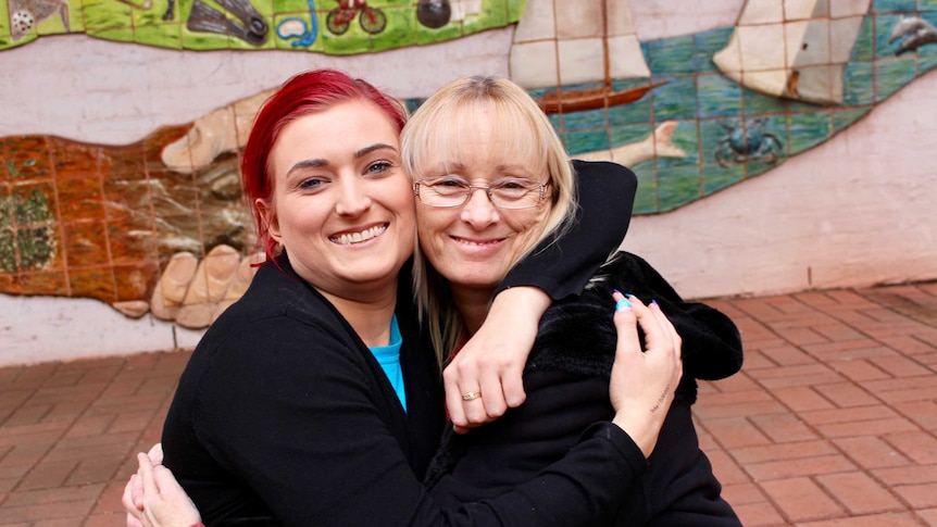 Karen Harrison and her daughter sit and hug