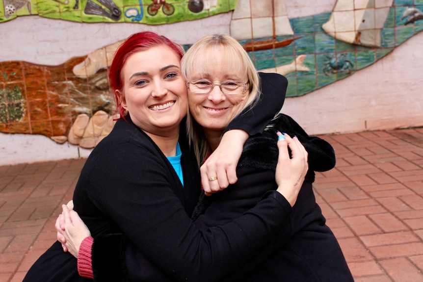 Karen Harrison and her daughter sit and hug