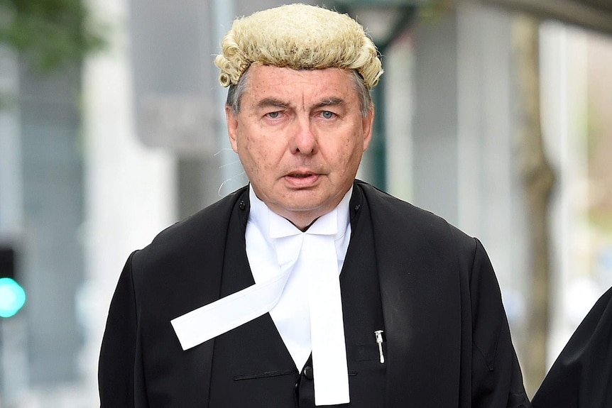 Walter Sofronoff dressed in court robes walks down a street in Brisbane.