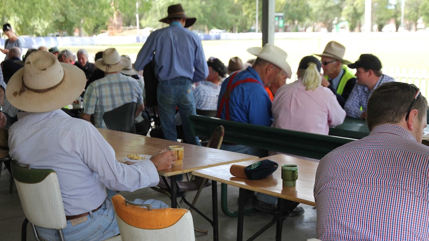 A farmer has morning tea at the NSW Sheep Dog Trials in Molong next to an empty seat