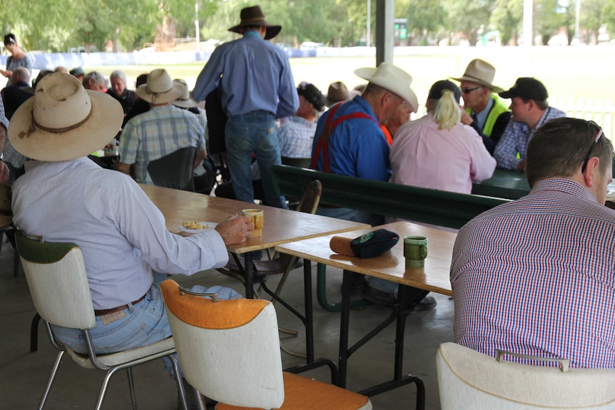 A farmer has morning tea at the NSW Sheep Dog Trials in Molong next to an empty seat