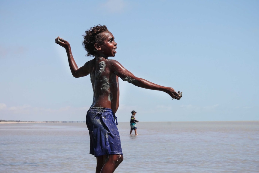 Young Gangalidda boy throws clay at the beach.