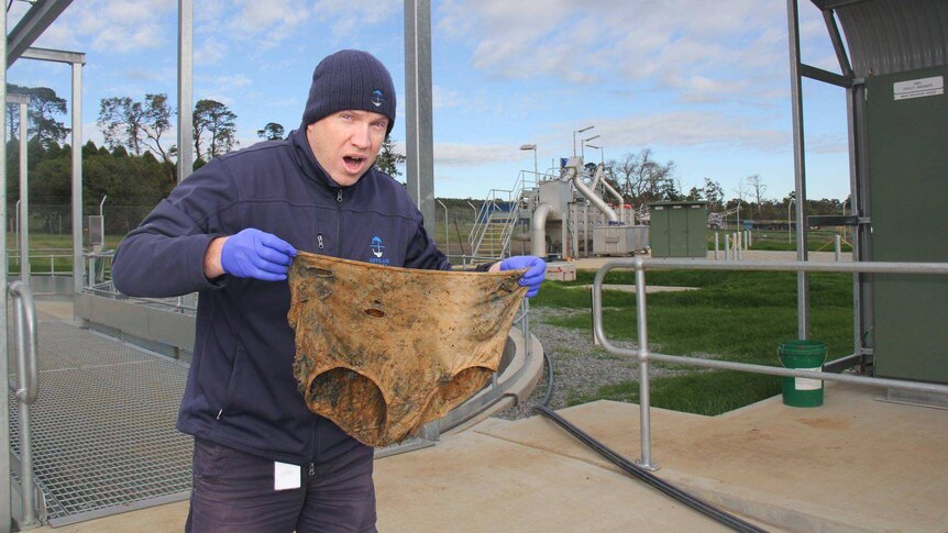 man holding large underpants from sewer