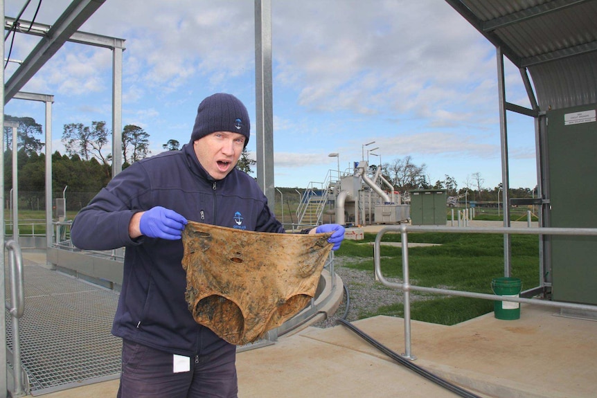 man holding large underpants from sewer