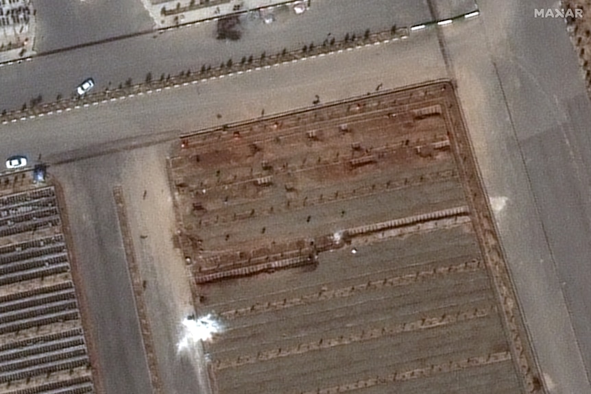 A satellite image shows a mass buriul site and a parge pile of white lime