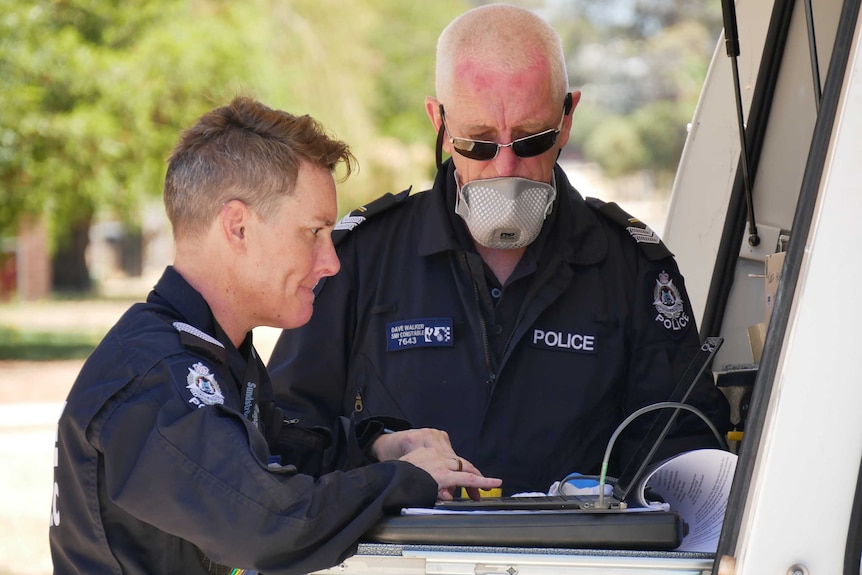 Two forensic police officers with specialist equipment.