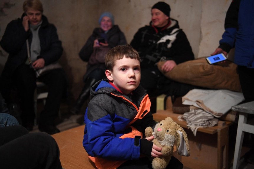 A young boy holds a toy rabbit.