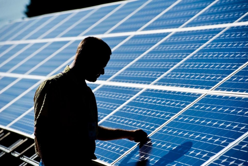 Silhouette of man checking solar panels