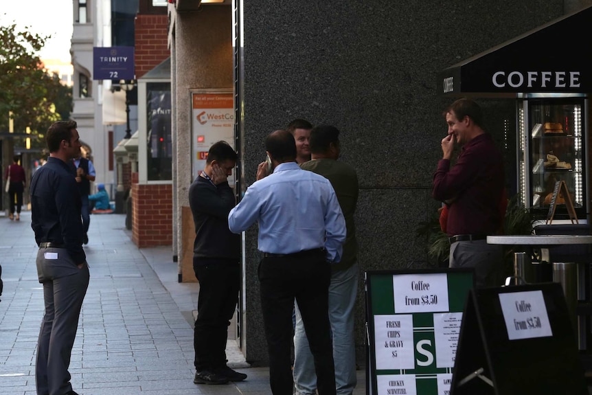 Several men stand outside a coffee stand on St Georges Terrace in Perth's CBD before work