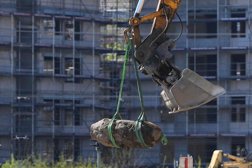 A WWII bomb is lifted out of the ground by a crane in Berlin, Friday, April 20, 2018.