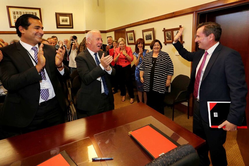 Mark McGowan waving as he enters a room of clapping colleagues