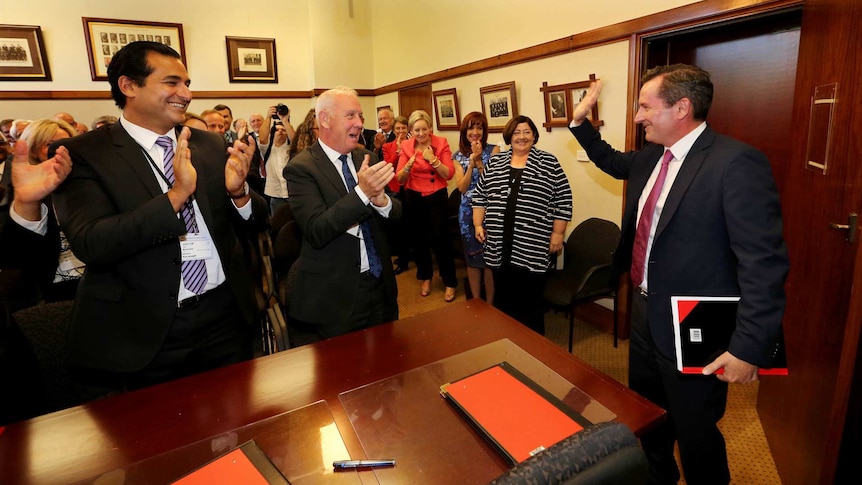 Mark McGowan waving as he enters a room of clapping colleagues