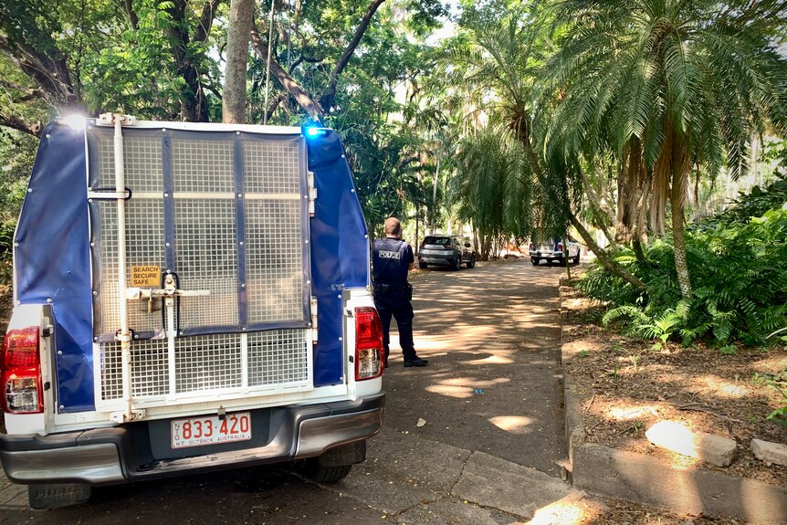Two police vans out the tree-lined entrance to a park.