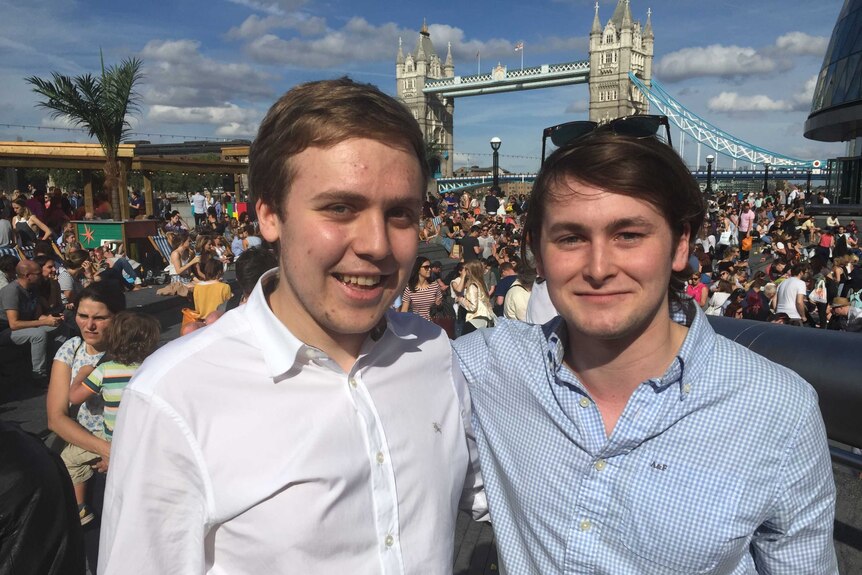 Flatmates Stephen Hedges and Ben Owens stand in front of crowds watching Wimbledon on the big screen in front of Tower Bridge