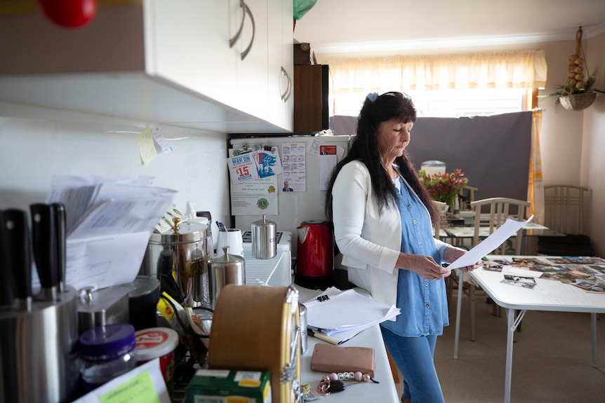 A woman reads a letter in her kitchen