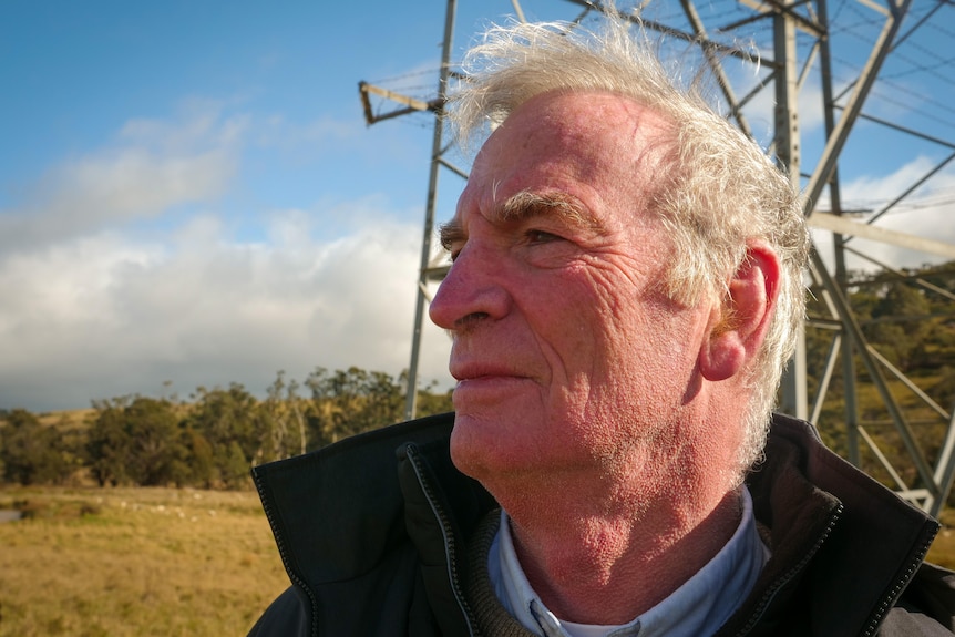 A man standing in front of a transmission line.