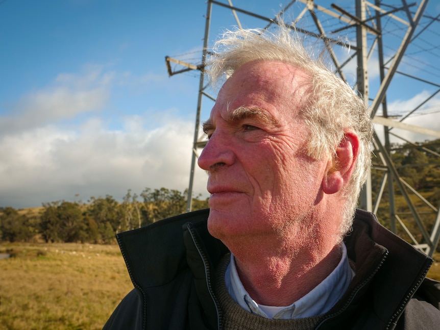 A man standing in front of a transmission line.