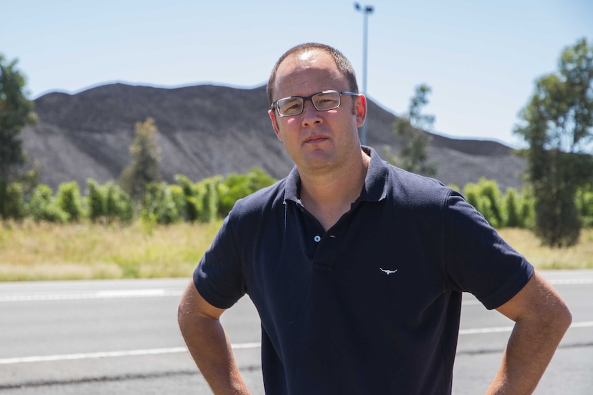 ABC National Reporting Team's Mark Willacy standing in front of coal stockpiles less than 1 kilometre from Jondaryan, Queensland