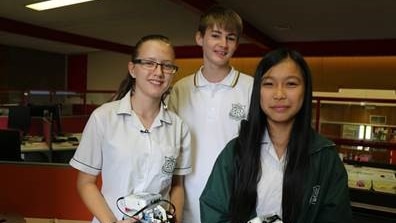 High school students stand with the Lego robot creations.