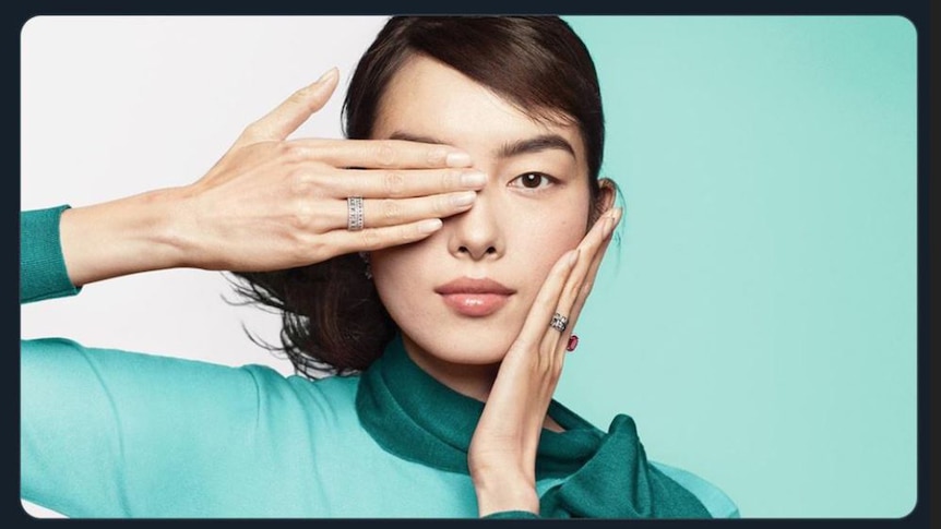 A screen shot of a Tiffany & Co advertisement of a woman with her hand over her eye.