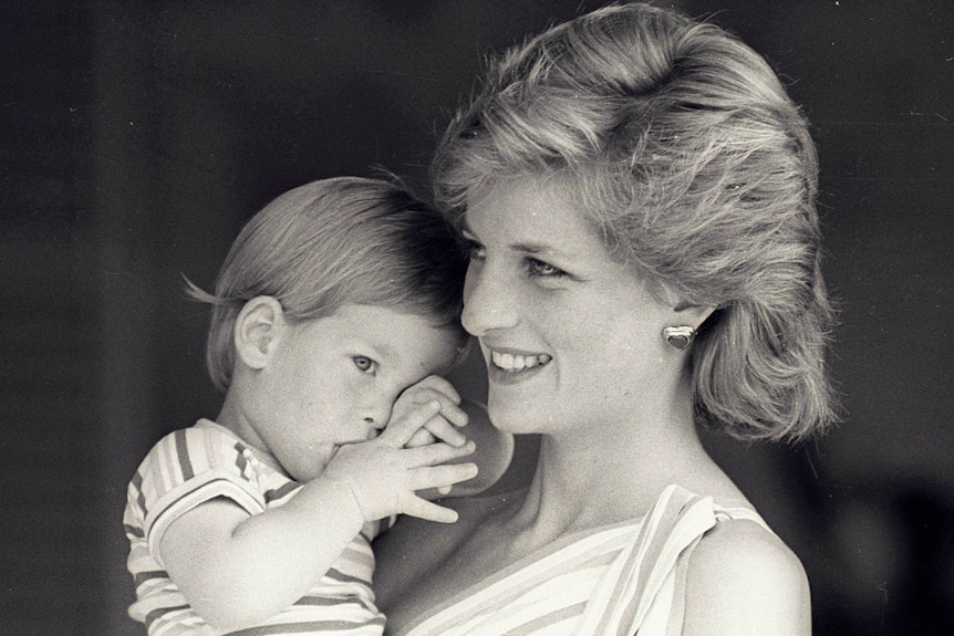 Princess Diana is holding a young Prince Harry.