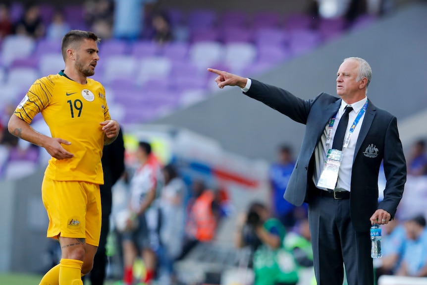 Graham Arnold points to the field as he directs Josh Risdon during the Asian Cup match against Jordan