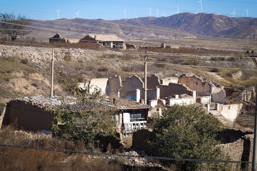 A rural Chinese village with wind farms in the distance