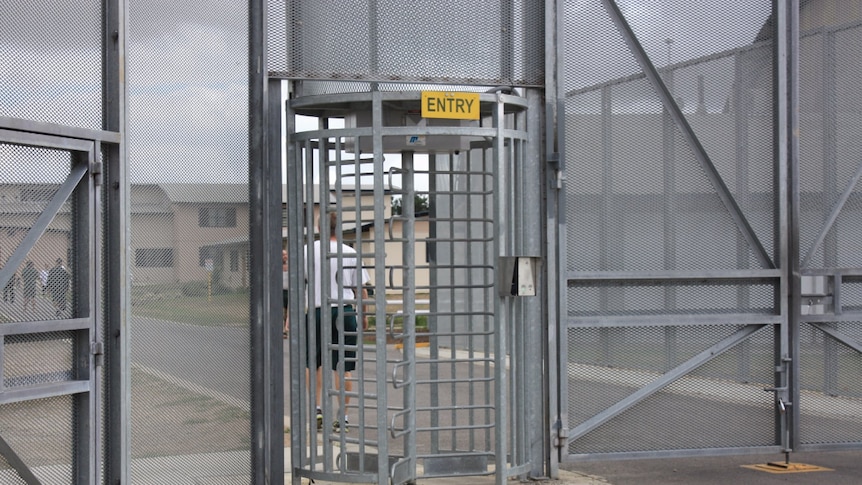 A revolving gate, below a sign labelled 'ENTRY', out the front of a prison yard.