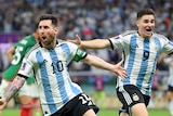 Lionel Messi holds his arms aloft alongside a celebrating teammate after scoring for Argentina