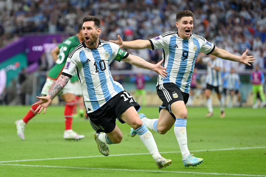 Lionel Messi holds his arms aloft alongside a celebrating teammate after scoring for Argentina