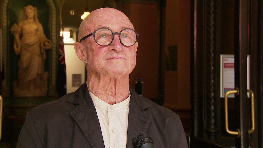 a man wearing glasses outside a court