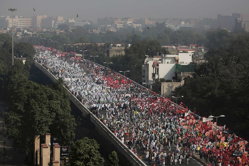 Farmers in white and red flood a street in New Delhi.