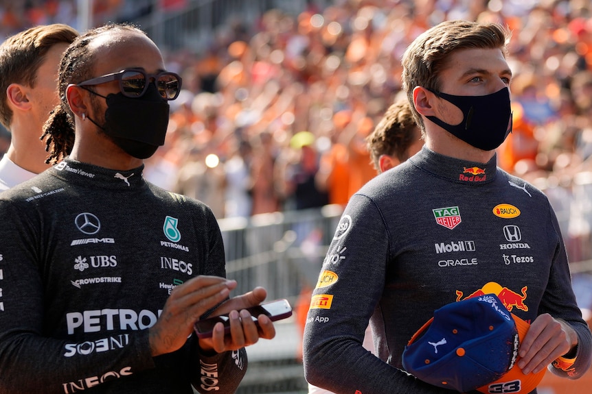 Two racing drivers standing during the national antham before a race.