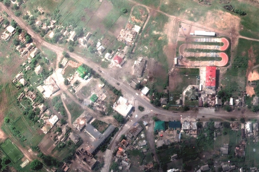 A satellite image shows damaged buildings and a tank on a road, in Lyman, Ukraine.