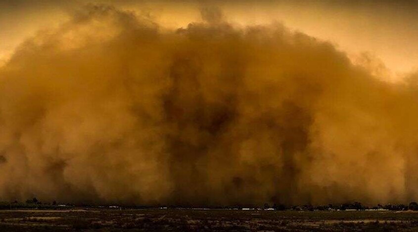 An orange and brown cloud of dust engulfs a town.