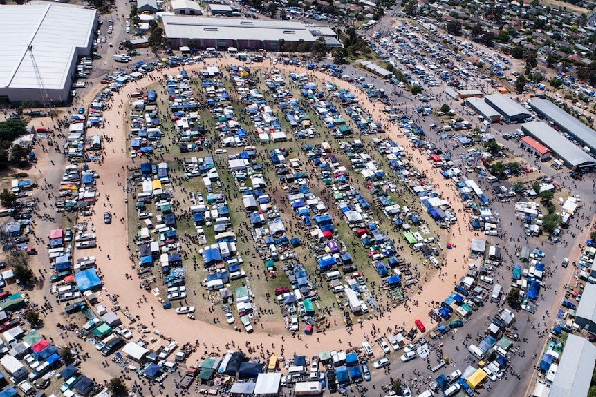 A crowd of tents can be seen above a trade and swap event at a showground.